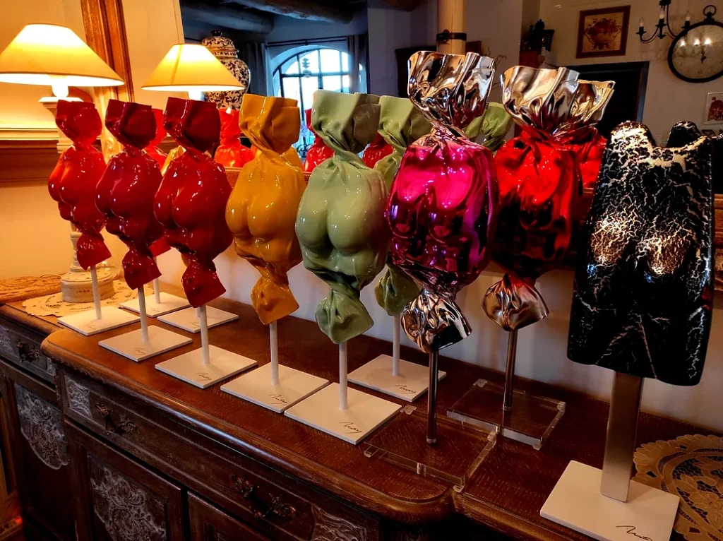 Série des sculptures sensuelles aux couleurs pop les Bonbons Candy par l'artiste sculpteur Arson et un Esculmau sculpture sensuelle fessue en forme de glace présentées sur un buffet